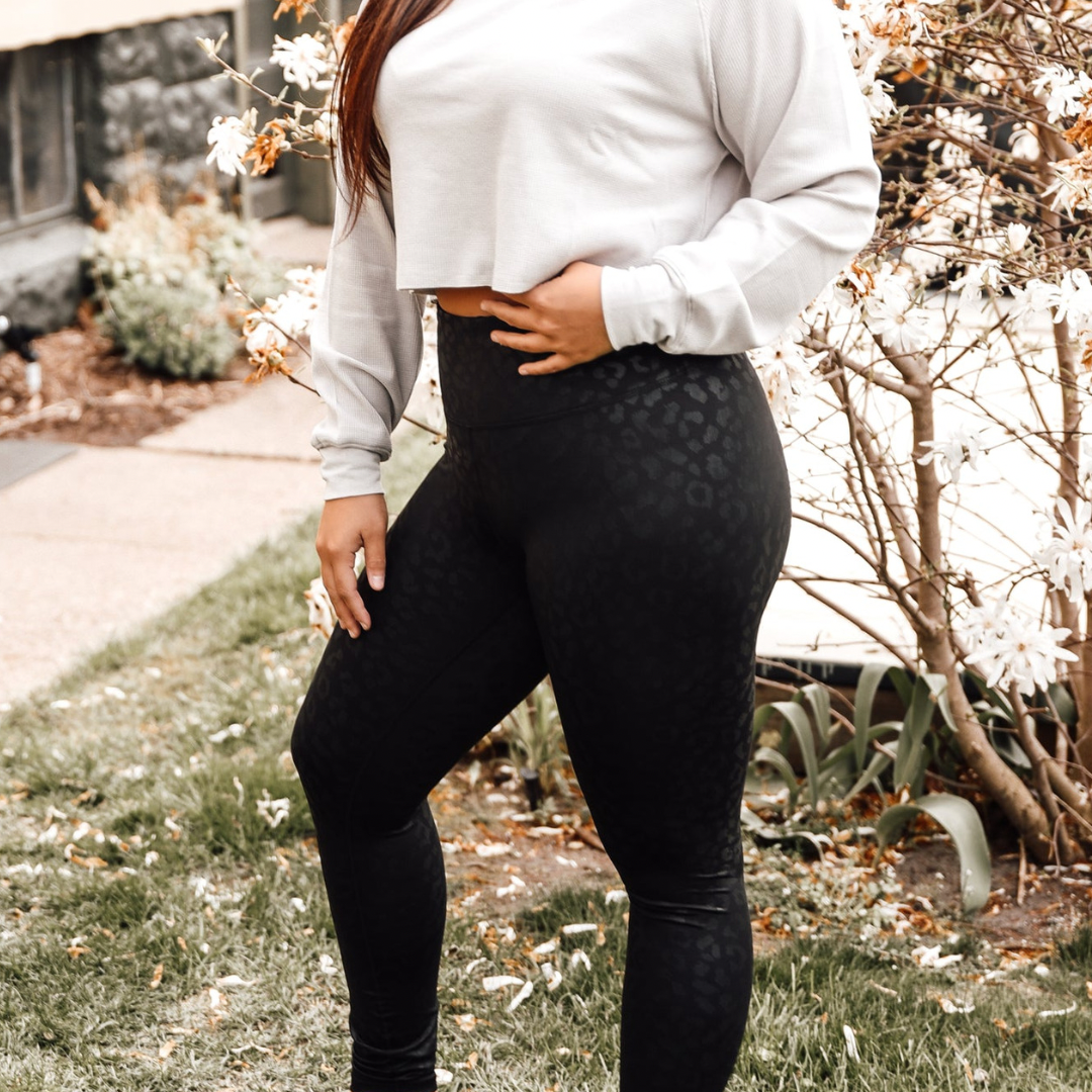 Woman wearing black leopard print leggings with cropped grey crewneck
