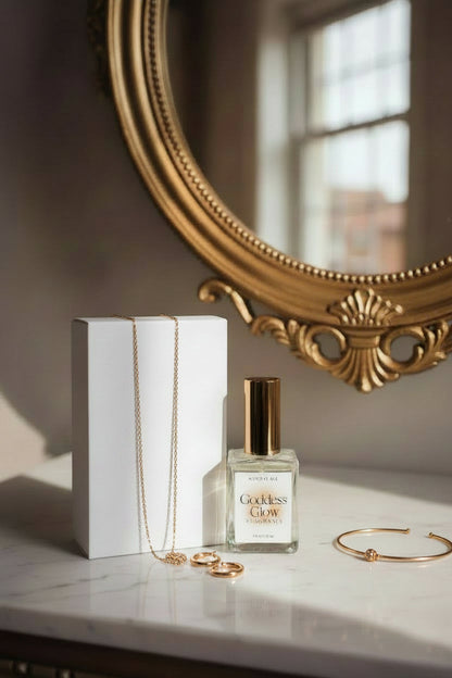 A bottle of Goddess Glow fragrance and box on a vanity in front of a gold mirror
