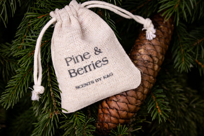 Small drawstring bag labeled 'Pine & Berries' on a pine branch with a pine cone.